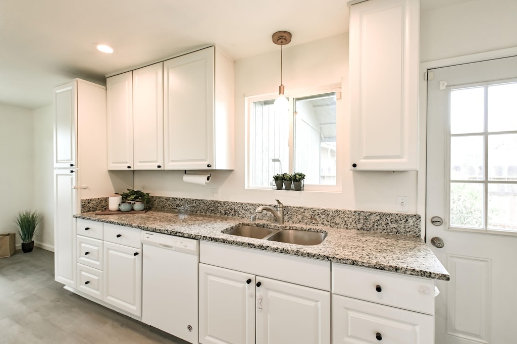 kitchen with dishwasher, sink, decorative light fixtures, and white cabinets