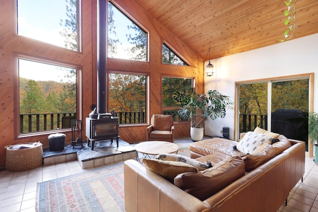 living room with a wood stove, wooden ceiling, high vaulted ceiling, wooden walls, and light tile patterned floors