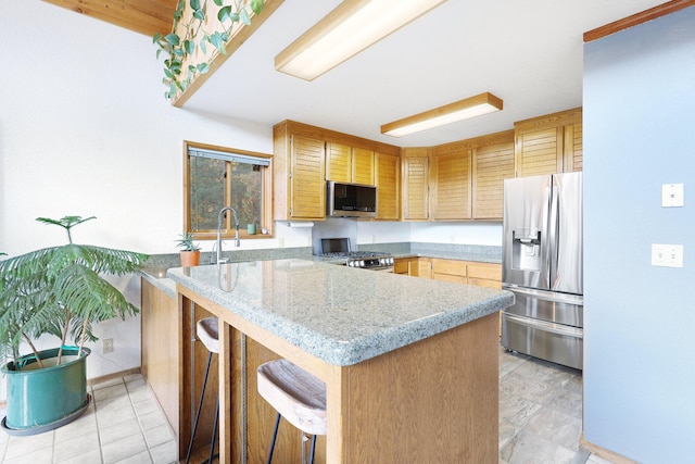 kitchen featuring kitchen peninsula, stainless steel appliances, light stone counters, and a breakfast bar area