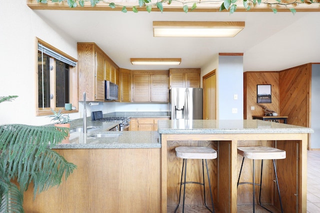 kitchen with kitchen peninsula, a kitchen breakfast bar, stainless steel appliances, and light stone counters