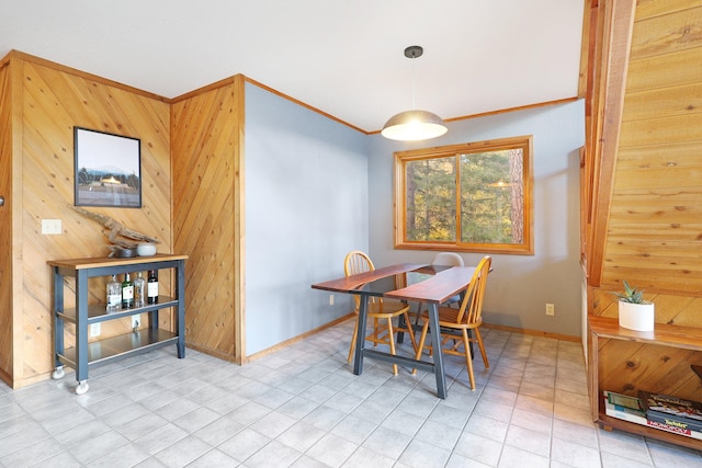 dining space with wood walls, light tile patterned floors, and crown molding