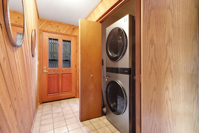 laundry area featuring light tile patterned floors, stacked washer and dryer, and wooden walls