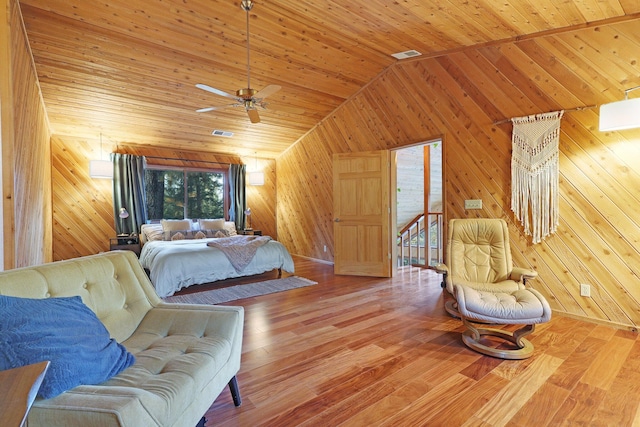 bedroom with wooden walls, hardwood / wood-style floors, wood ceiling, and vaulted ceiling