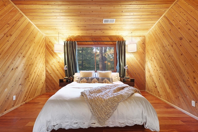 bedroom with wooden walls, wooden ceiling, vaulted ceiling, and wood-type flooring