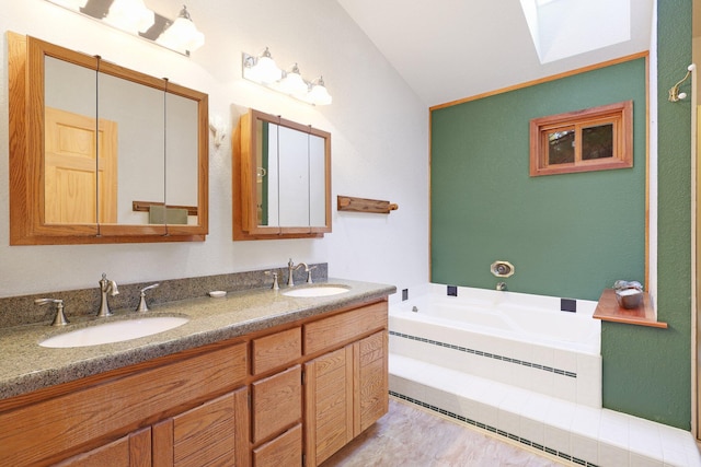 bathroom with a bathtub, vanity, and vaulted ceiling with skylight