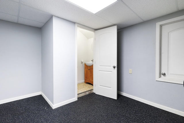 basement featuring a paneled ceiling and sink