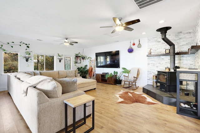 living room featuring hardwood / wood-style flooring, ceiling fan, and a wood stove