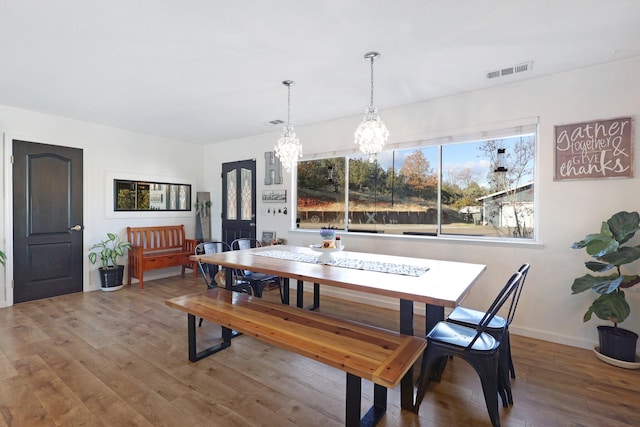 dining space featuring wood-type flooring and an inviting chandelier