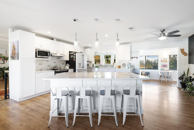 kitchen with a spacious island, white cabinetry, and appliances with stainless steel finishes