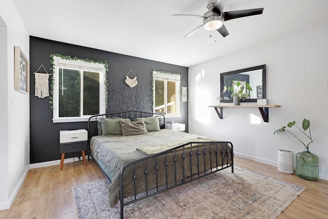 bedroom featuring hardwood / wood-style flooring, ceiling fan, and multiple windows