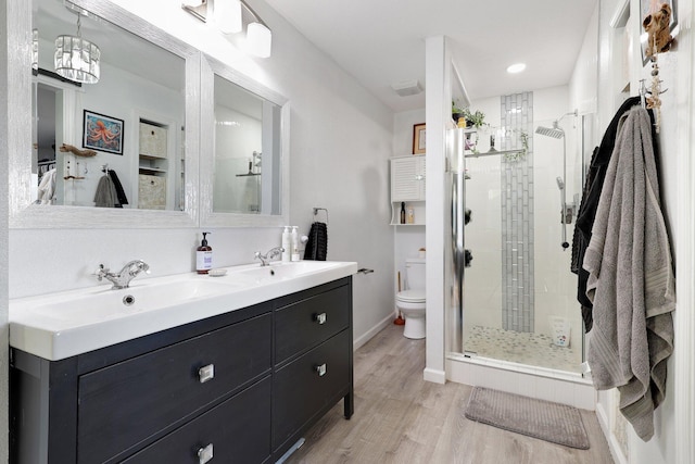 bathroom featuring vanity, wood-type flooring, an enclosed shower, and toilet