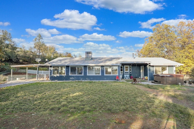 back of house featuring a lawn, a patio area, and a hot tub