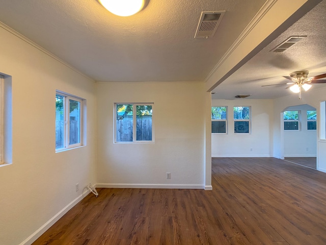 unfurnished room with dark hardwood / wood-style floors, a healthy amount of sunlight, a textured ceiling, and ornamental molding