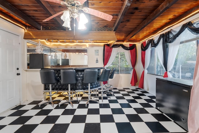 interior space featuring beam ceiling, ceiling fan, stainless steel fridge, and wooden ceiling