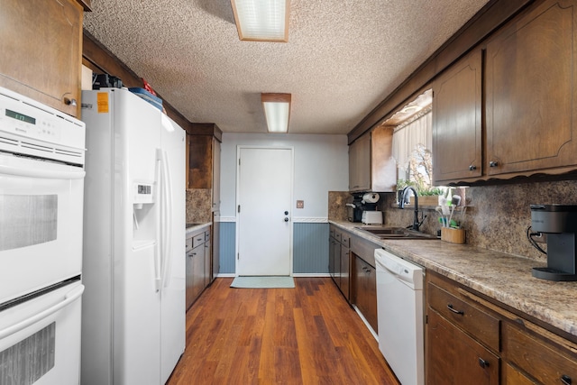 kitchen with sink, white appliances, backsplash, and dark hardwood / wood-style flooring