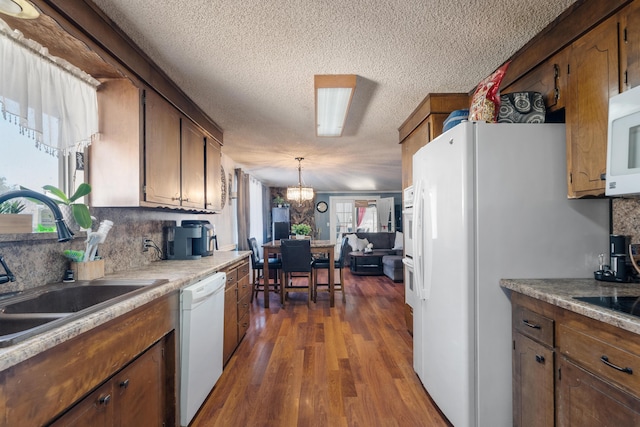 kitchen with decorative backsplash, white appliances, dark wood-type flooring, pendant lighting, and sink