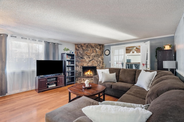 living room with a textured ceiling, crown molding, a fireplace, and wood-type flooring