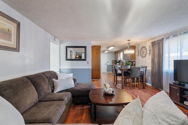 living room with a notable chandelier, a textured ceiling, and hardwood / wood-style floors