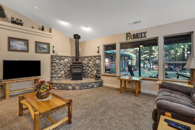 living room with a wood stove, vaulted ceiling, and carpet
