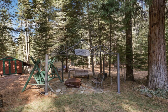 view of yard featuring a shed, a playground, and a fire pit