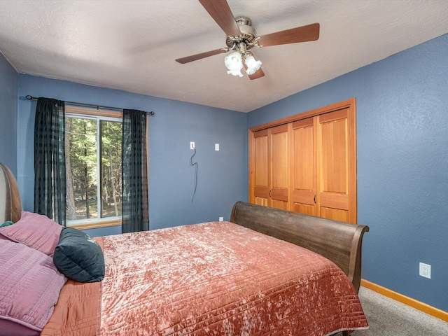 carpeted bedroom with ceiling fan, a textured ceiling, and a closet