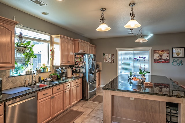 kitchen with a wealth of natural light, sink, decorative light fixtures, and appliances with stainless steel finishes