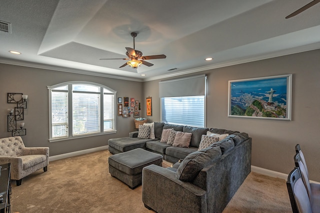 carpeted living room featuring ornamental molding, ceiling fan, and a tray ceiling