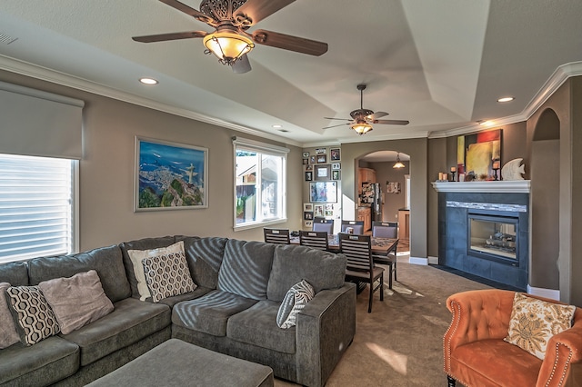 living room with ceiling fan, carpet flooring, ornamental molding, and a fireplace