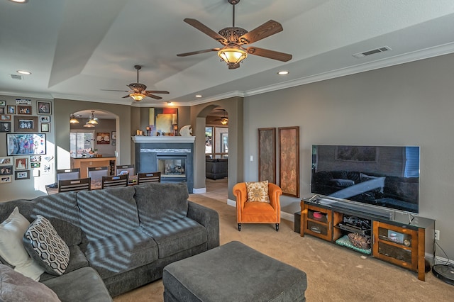 carpeted living room featuring ceiling fan, a tray ceiling, and ornamental molding