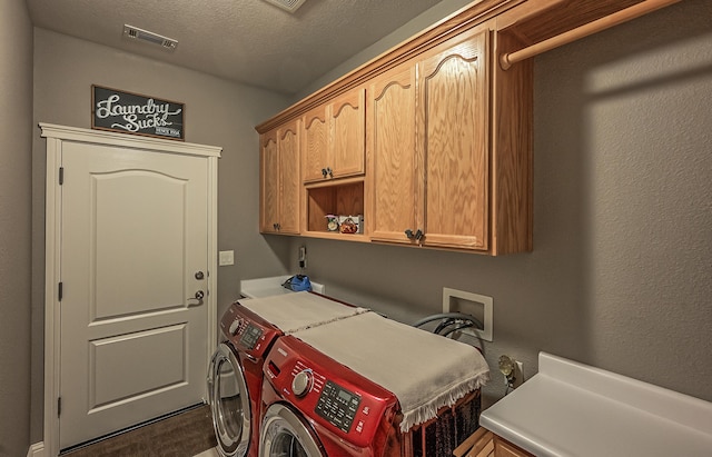 laundry room featuring a textured ceiling, cabinets, and washing machine and clothes dryer