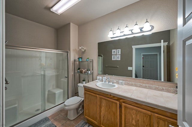 bathroom featuring walk in shower, vanity, toilet, and tile patterned flooring