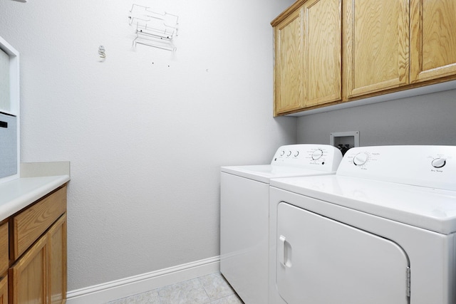 laundry area featuring washer and dryer, light tile patterned floors, and cabinets