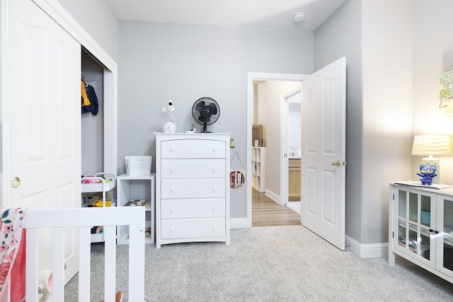 bedroom with a nursery area, a closet, and light colored carpet