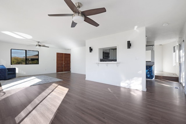 unfurnished living room featuring dark wood-type flooring and ceiling fan