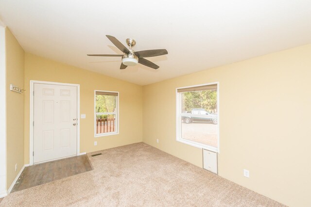 carpeted spare room featuring ceiling fan, a healthy amount of sunlight, and vaulted ceiling