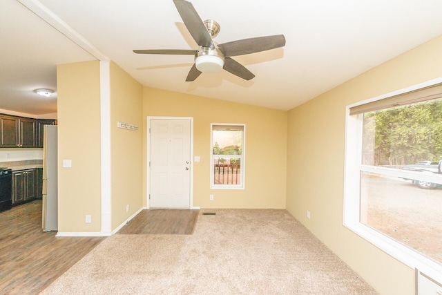 spare room with light wood-type flooring, a healthy amount of sunlight, ceiling fan, and vaulted ceiling