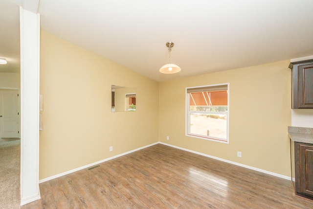 unfurnished dining area featuring light hardwood / wood-style floors and lofted ceiling