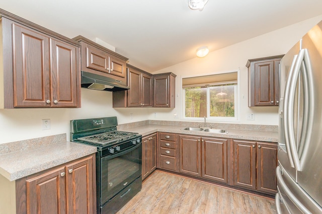 kitchen featuring gas stove, stainless steel fridge, light wood-type flooring, sink, and vaulted ceiling