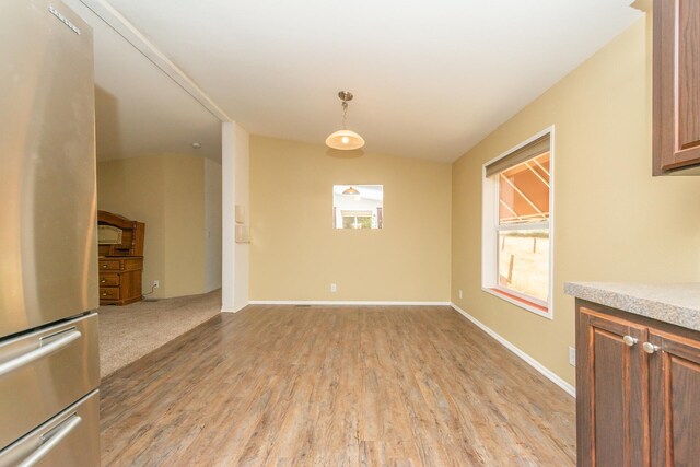 unfurnished dining area featuring light wood-type flooring and lofted ceiling