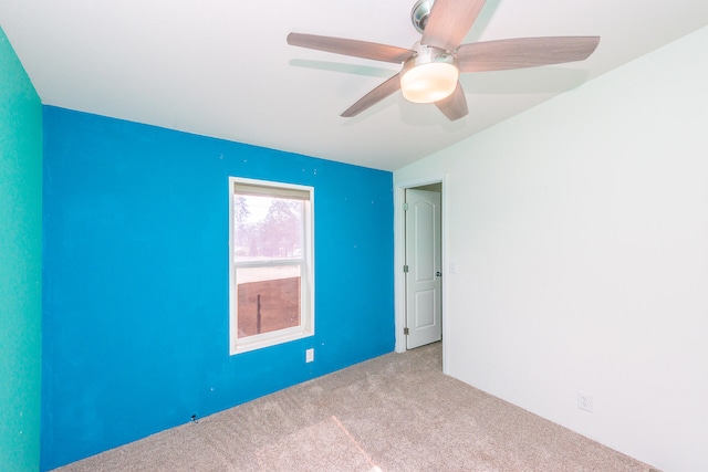 empty room featuring light colored carpet, ceiling fan, and vaulted ceiling