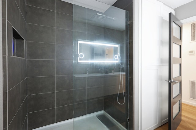 bathroom featuring hardwood / wood-style floors and a tile shower