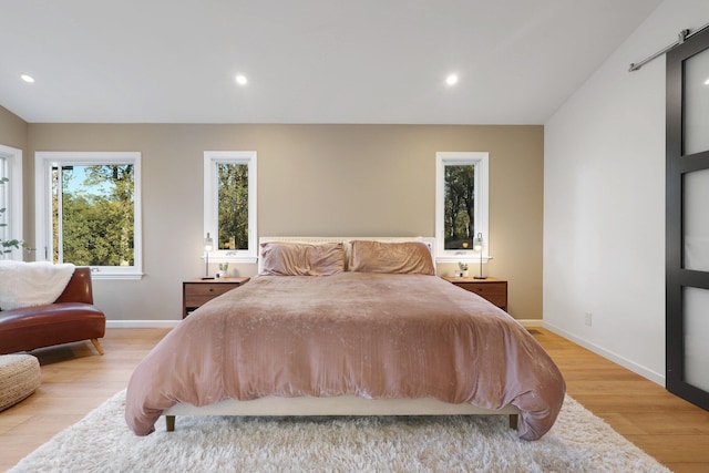 bedroom with a barn door and light hardwood / wood-style floors