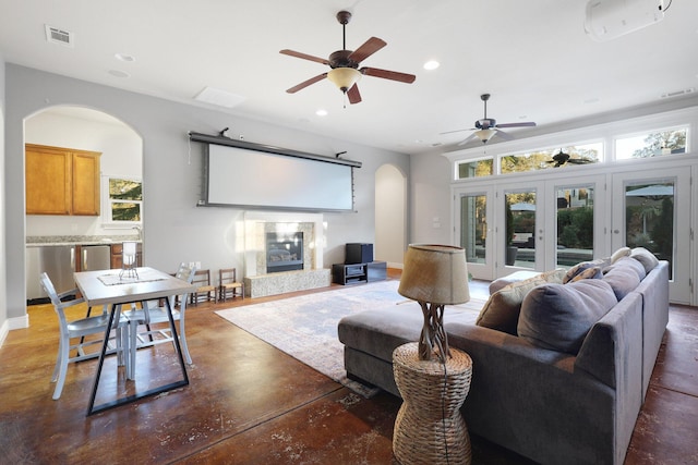 living room featuring a fireplace, ceiling fan, and french doors