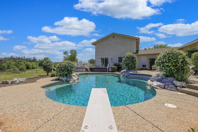 view of pool with a diving board and a patio area