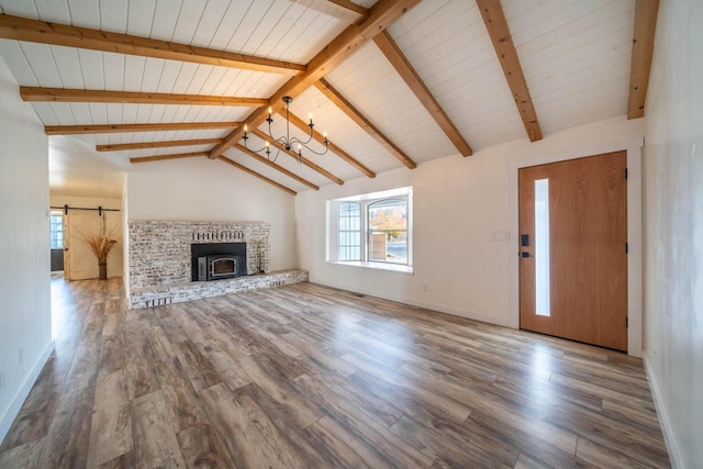 unfurnished living room with wood finished floors, a notable chandelier, vaulted ceiling with beams, and a barn door