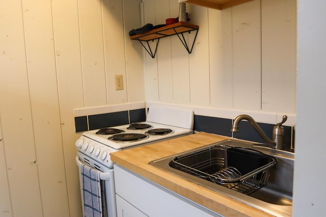 kitchen featuring white cabinetry, sink, butcher block countertops, and electric stove