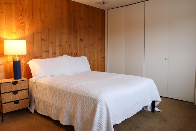 carpeted bedroom with a closet and wood walls