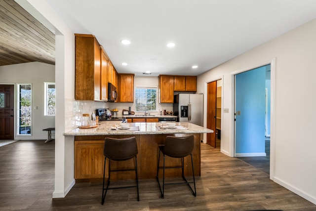 kitchen featuring sink, kitchen peninsula, appliances with stainless steel finishes, lofted ceiling, and dark wood-type flooring