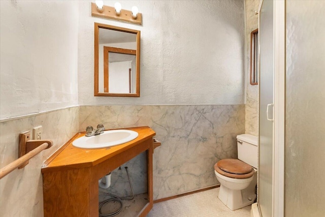 bathroom with toilet, tile walls, and sink