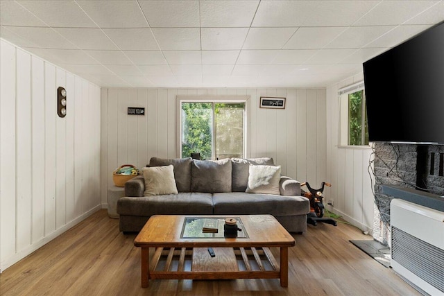 living room with light hardwood / wood-style floors and wood walls